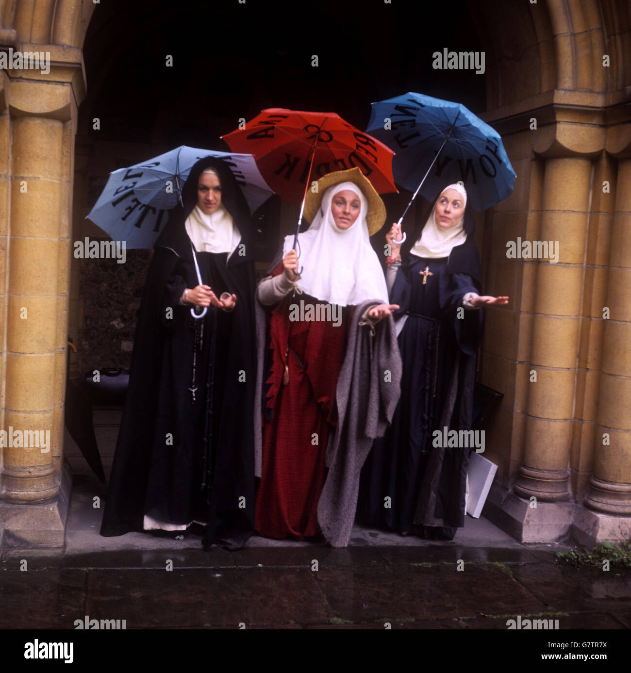 Jeannie Fisher (nun), Barbara Jefford (wife of Bath) and Marion Diamond (Prioress) cope with rain during filming at Canterbury Cathedral, to be screened later in the year. Stock Photo