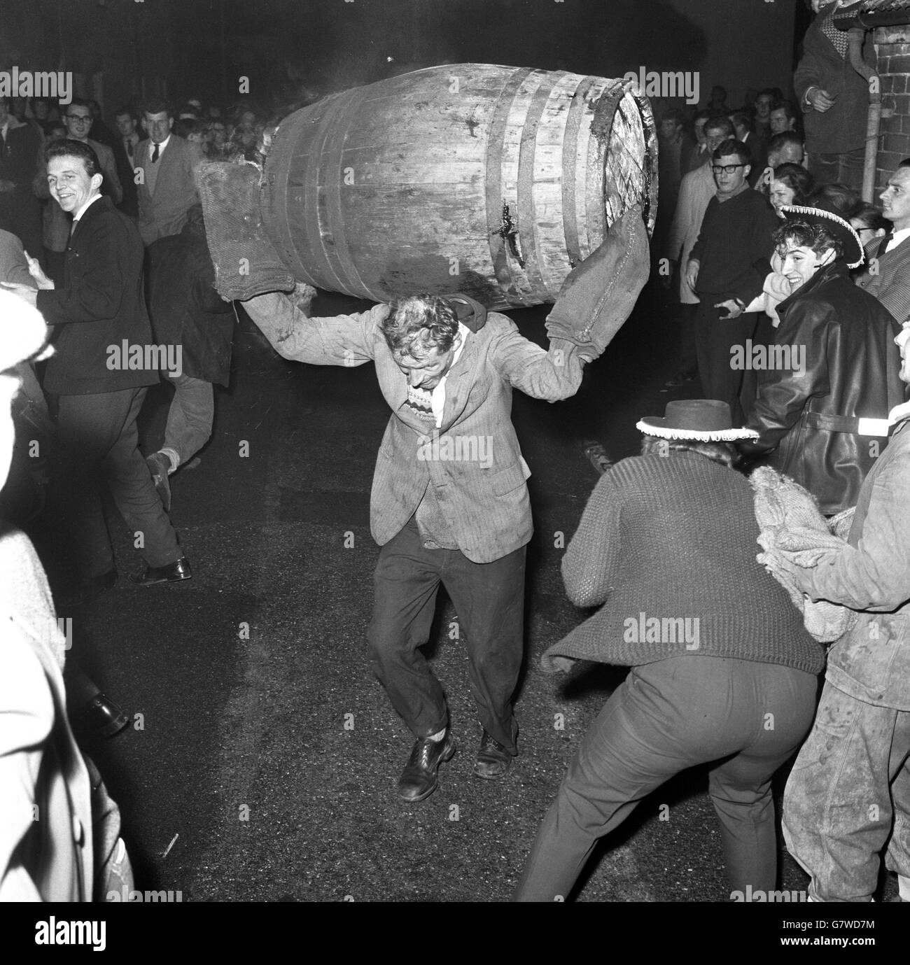 Tar Barrel Burning Ceremony - Ottery St Mary's. Crowds scatter as a participant dashes away with his burning barrel. Stock Photo