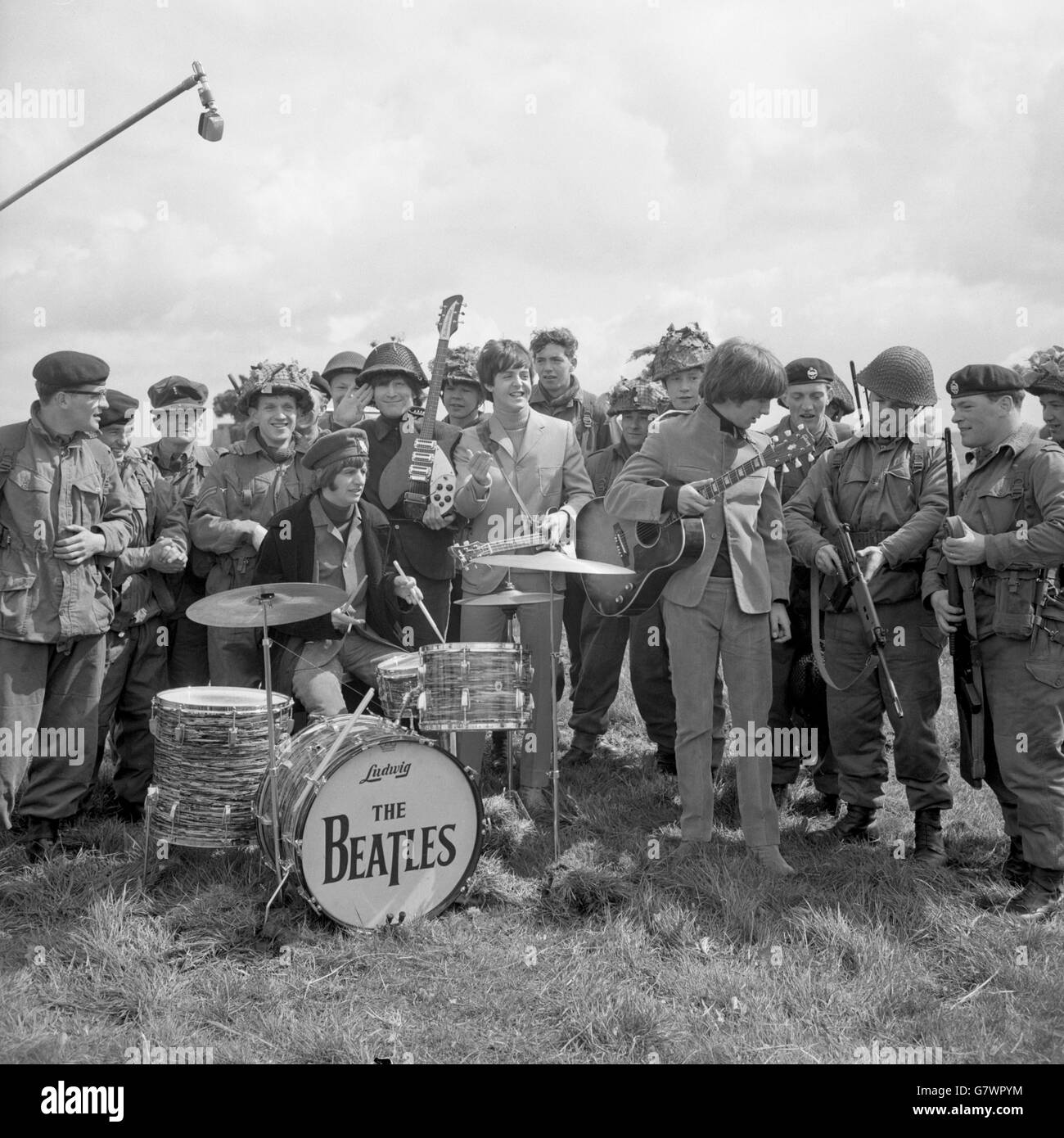 The Beatles play with an Army audience when on location shooting for their new film at Larkhill. Left to right - Ringo Starr (on drums), John Lennon, Paul McCartney and George Harrison. Stock Photo