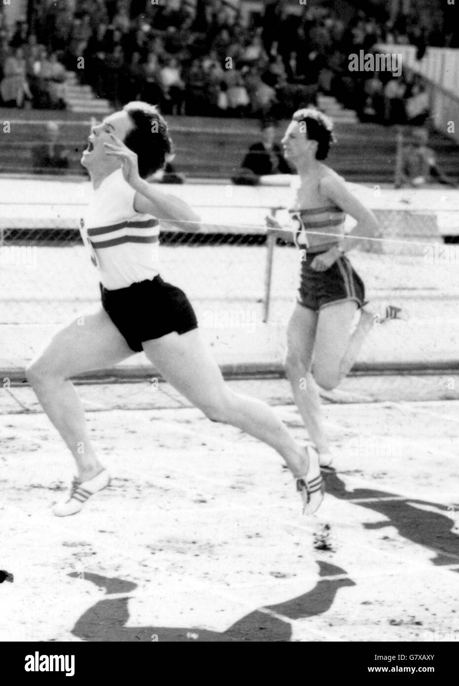 With both feet off the ground, June Paul (Sparton Ladies' A.C.) reaches the tape to win the 220 yards final in 23.8 seconds at the Women's Amateur Athletic Association Championships at White City Stadium, London. Finishing second is Jean Scrivens (Selsonia LAC) in the background. Stock Photo