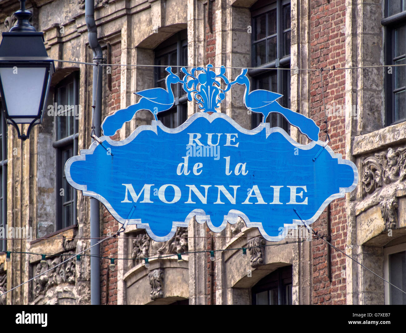 LILLE, FRANCE - JUNE 08, 2014:  Sign above Rue de la Monnaie, one of the oldest streets in the city with old buildings in background Stock Photo