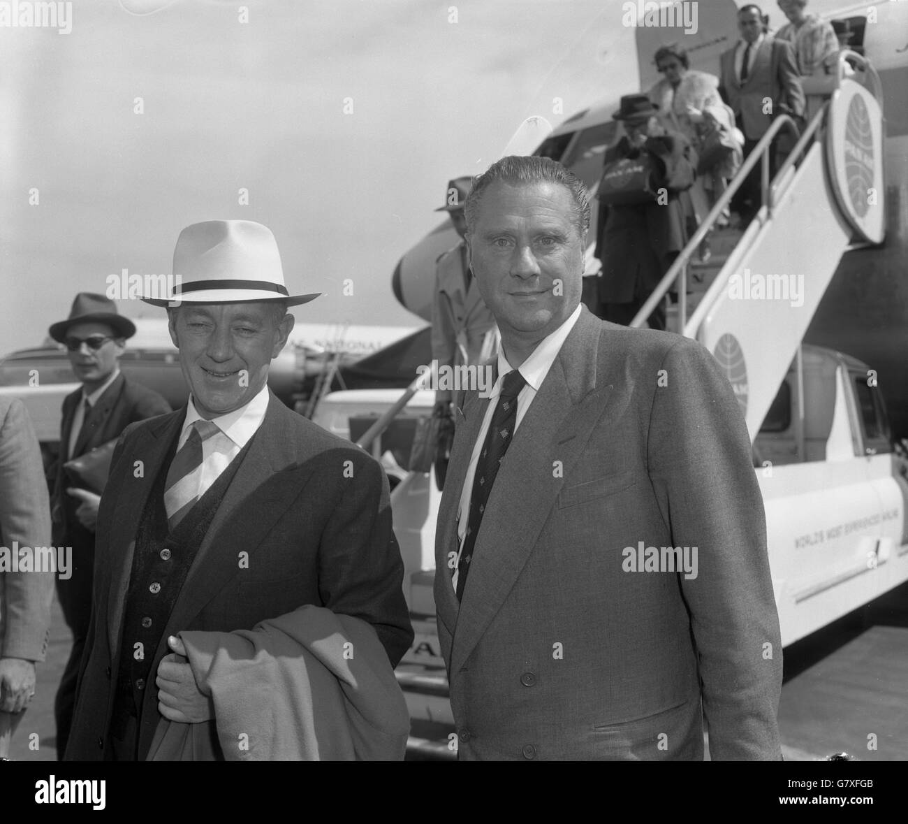 Sir Alec Guinness (l) and producer-director Sir Carol Reed arrived at London Airport from Havana after filming location scenes for 'Our Man in Havana', which is to be completed at Shepperton. Stock Photo