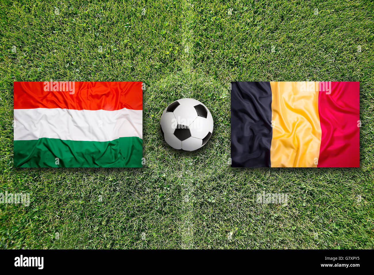 Hungary vs. Belgium flags on green soccer field Stock Photo