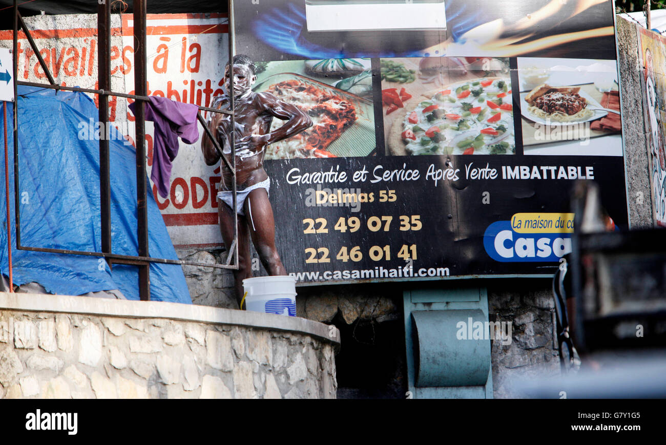 June 27, 2016 - Petionville, Florida, U.S. - 061010   (Lannis Waters/The Palm Beach Post)  PETIONVILLE, HAITI - A man takes a bath by a makeshift tent overlooking the main road through Petionville and Place St. Pierre, where there is a large refugee camp.  She shows how they stand up when it rains and try to direct the water away from leaks; what does come in they collect in buckets. (Credit Image: © Lannis Waters/The Palm Beach Post via ZUMA Wire) Stock Photo