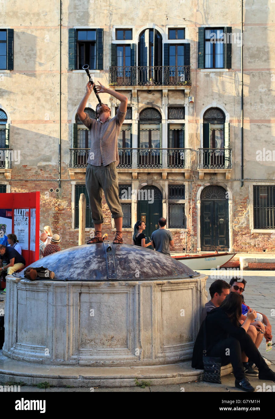 Busker street musician playing on a water well in Venice Stock Photo