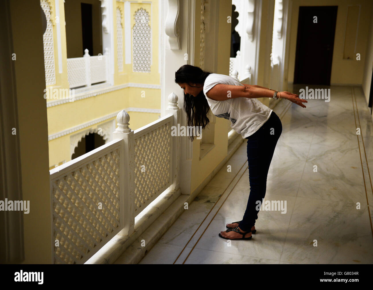 Young woman with luscious locks doing yoga exercises for health and fitness concept in balcony outside her bedroom. Stock Photo
