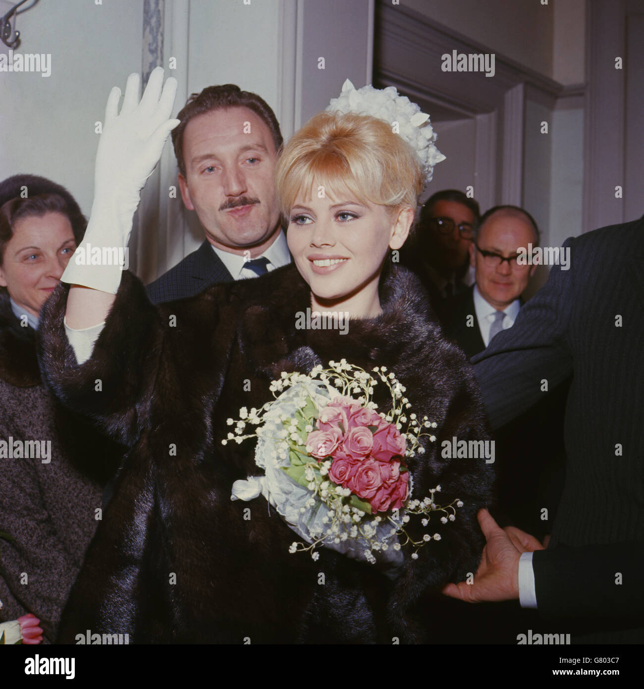 Swedish actress Britt Ekland waves to photographers after her wedding to English actor Peter Sellers at Guildford registery office, Surrey. The couple had known each other only a month. The bride is wearing a gown by Norman Hartnell and she carries pink roses and lillies of the valley. Her hat is a small pillbox covered in white fantasy flowers. Sellers wears a dark blue suit. After the ceremony, more than 1000 fans came to see the couple leave in their car. Stock Photo