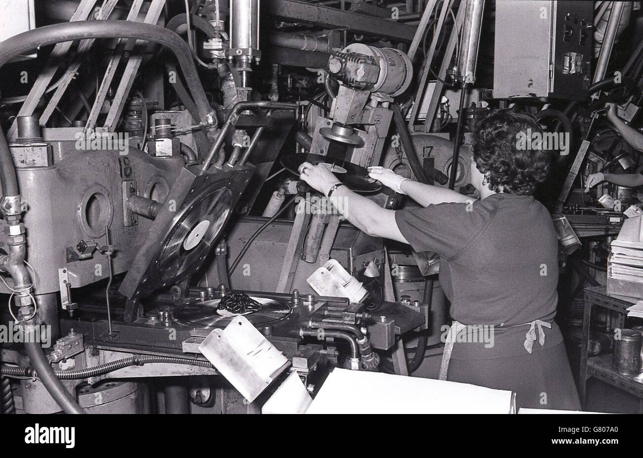 1970s, female factory worker using a machine or tool to produce LP's or vinyl records. Stock Photo