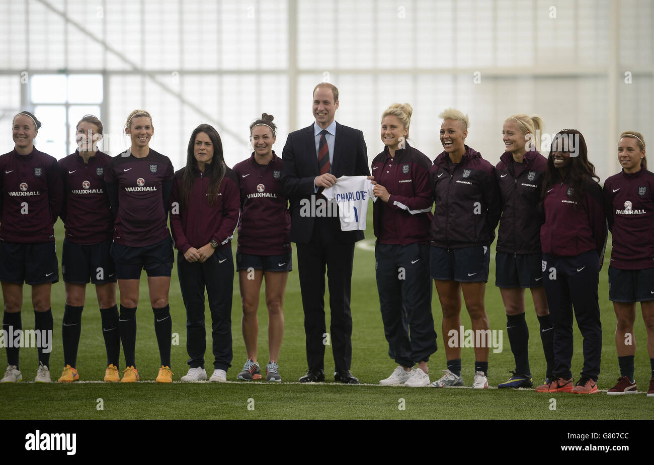 The Duke of Cambridge is presented with a football shirt for his daughter Princess Charlotte by the England women senior football team train during a visit to the FA National Football Centre, St George's Park in Burton-upon-Trent, Staffordshire. Stock Photo