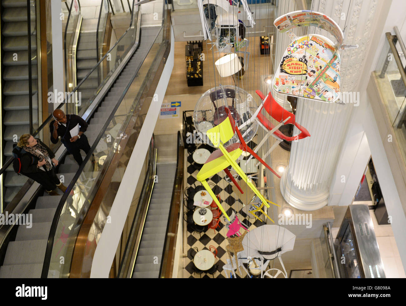 A new art installation of hanging chairs all individually designed by 90 artists for the charity Art Room are on display in the atrium at Selfridges in central London. Stock Photo