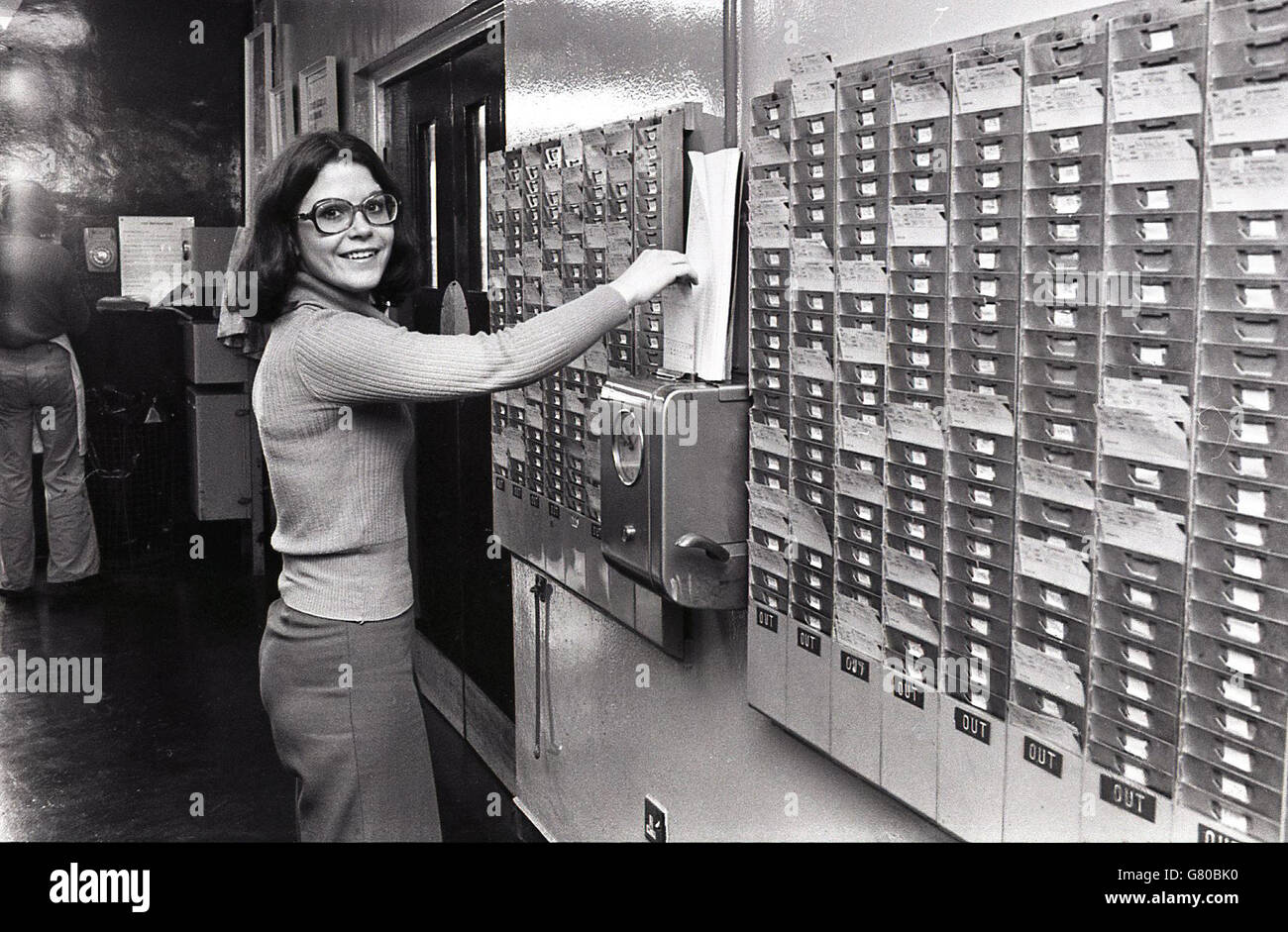 1970s, historical, female clocking in at work by putting her employee
