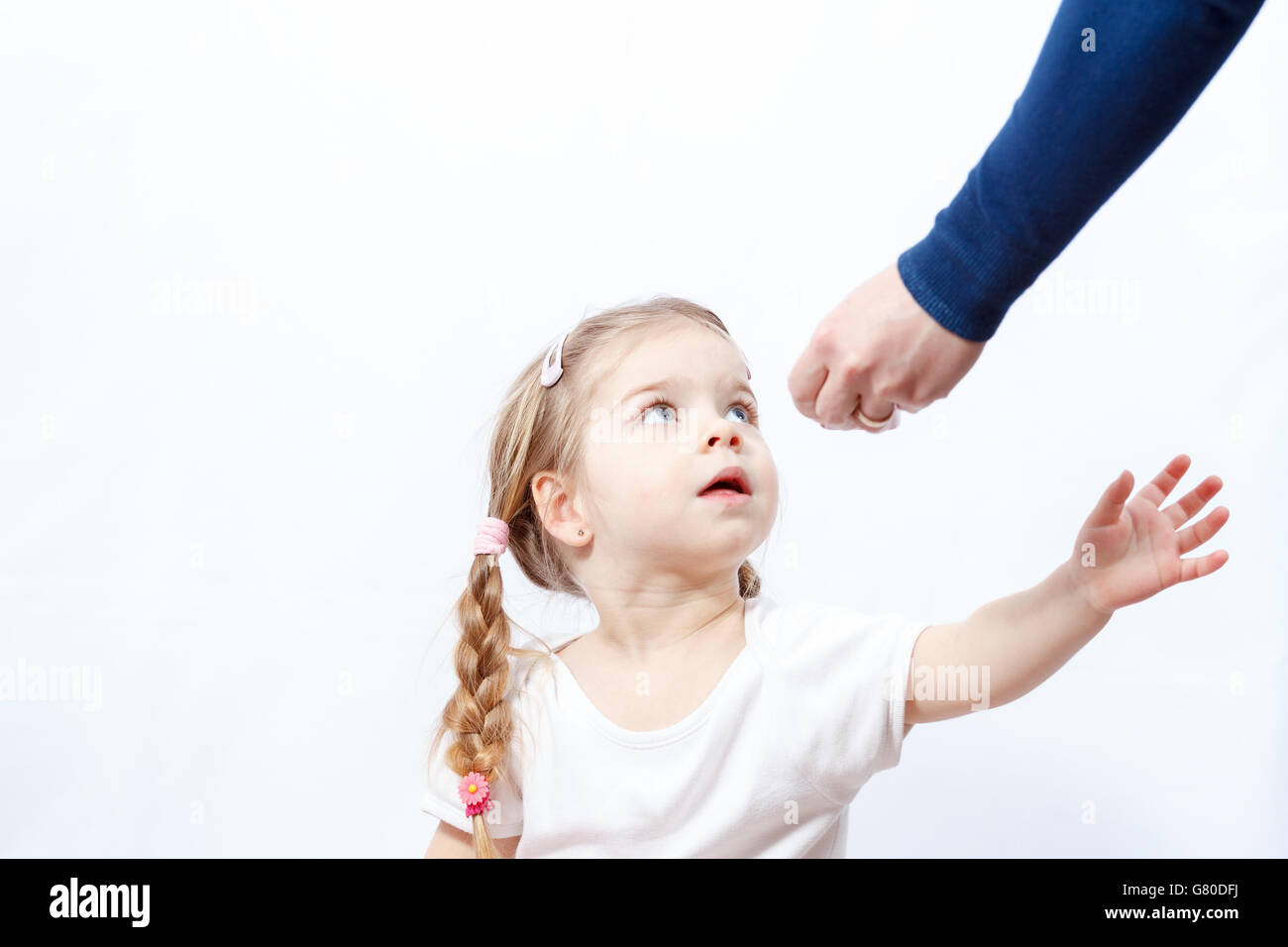 Little blonde baby girl grabs hand for items provided by her mother's