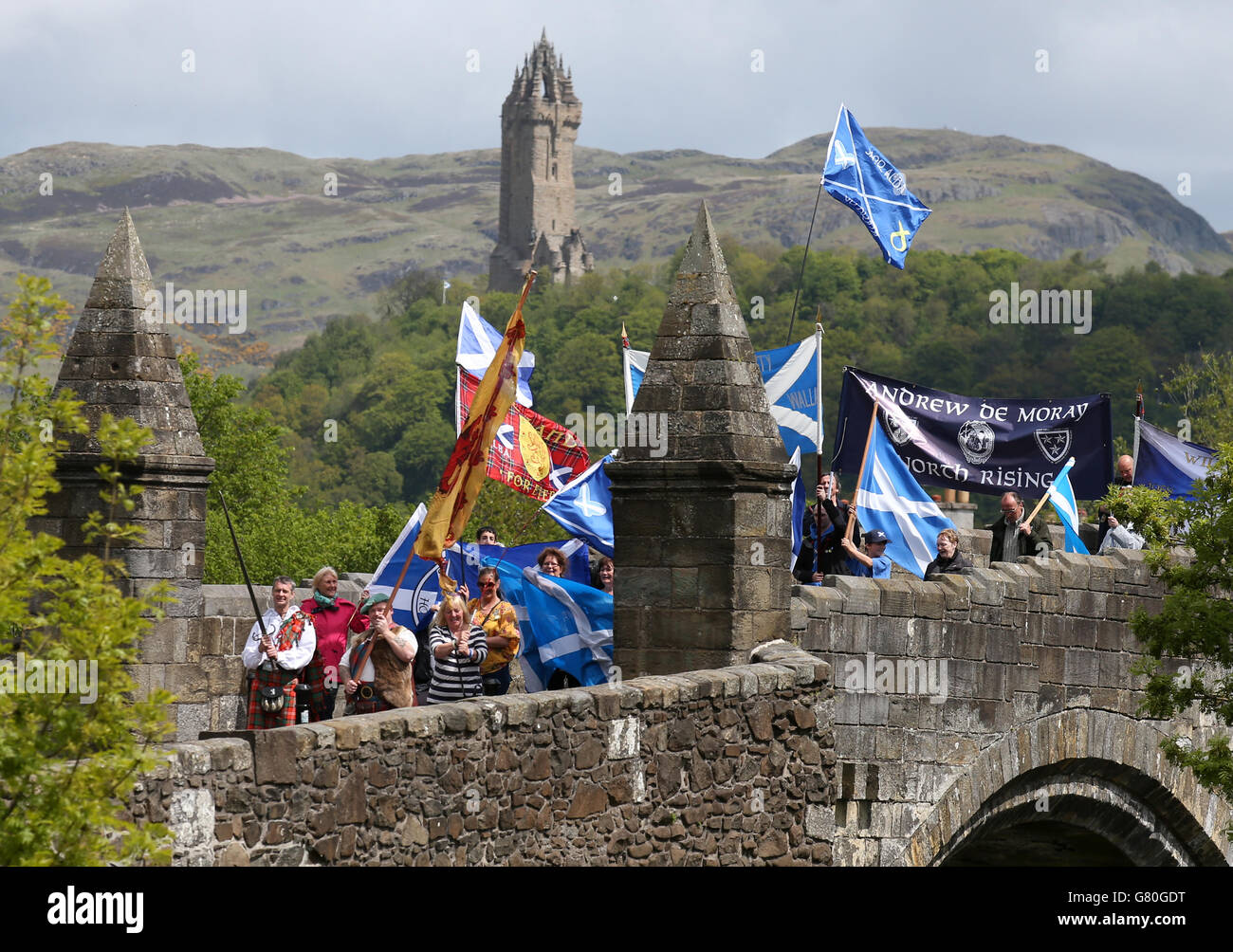 People wave Saltire flags on Stirling Bridge in front of the Wallace Monument as a memorial is unveiled at the site of the 'Braveheart battle', where William Wallace and Andrew de Moray led Scotland to victory at the Battle of Stirling Bridge in 1297. Stock Photo