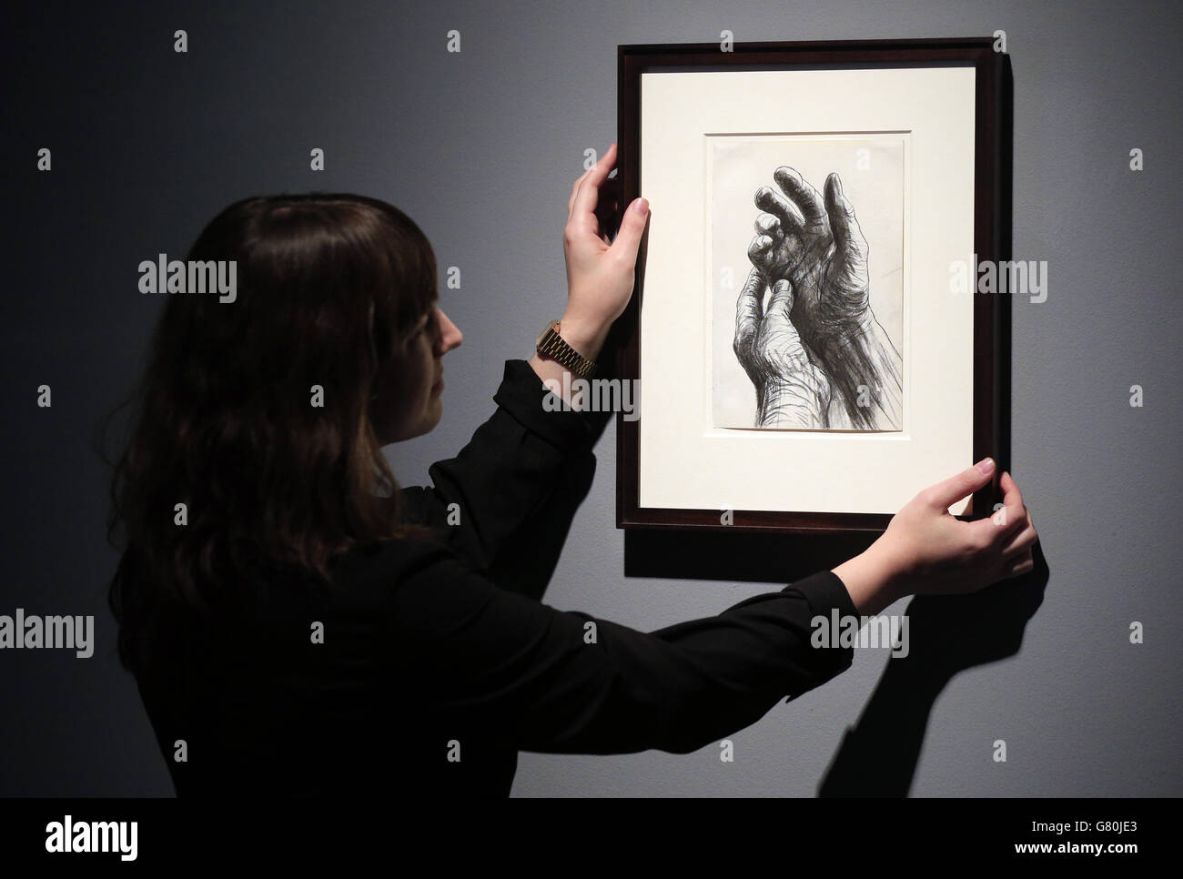 A gallery assistant adjusts 'The Artist's Hands' by Henry Moore during a press preview for 'Reflections on the Self', an exhibition of self portraiture at Christie's Mayfair. Stock Photo