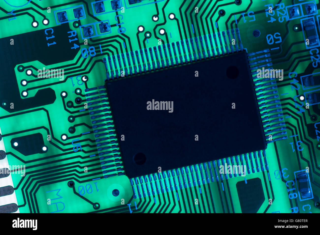 Technology concept. Circuit board / pcb showing components lit with blue and green light. Wiring inside computer, circuit close up, electronics Stock Photo