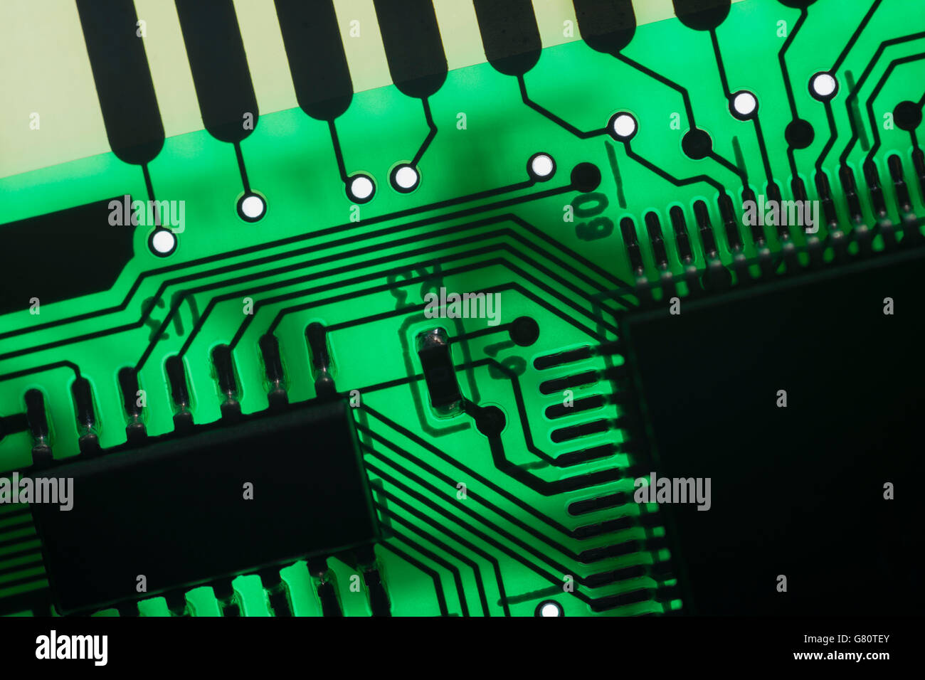 Computer technology concept. Circuit board / pcb showing components backlit with green light. Wiring inside computer, circuit close up, electronics Stock Photo