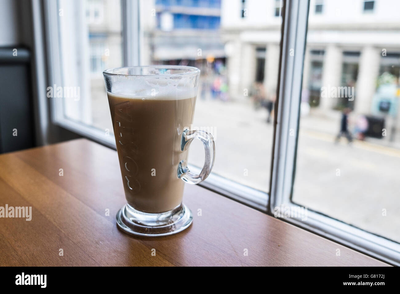 A coffee latte on a table next to a window. Stock Photo