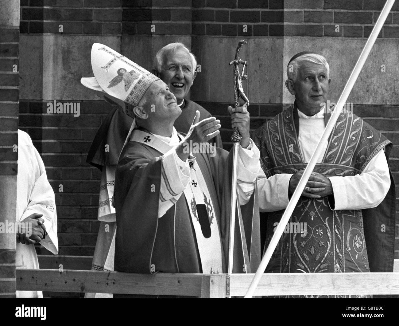 Pope John Paul II looks upwards from the balcony on the exterior of Westminster Cathedral, after celebrating Mass, and blessed the crowds. With him are Cardinal Basil Hume, and the Archbishop of Westminster (right). Stock Photo