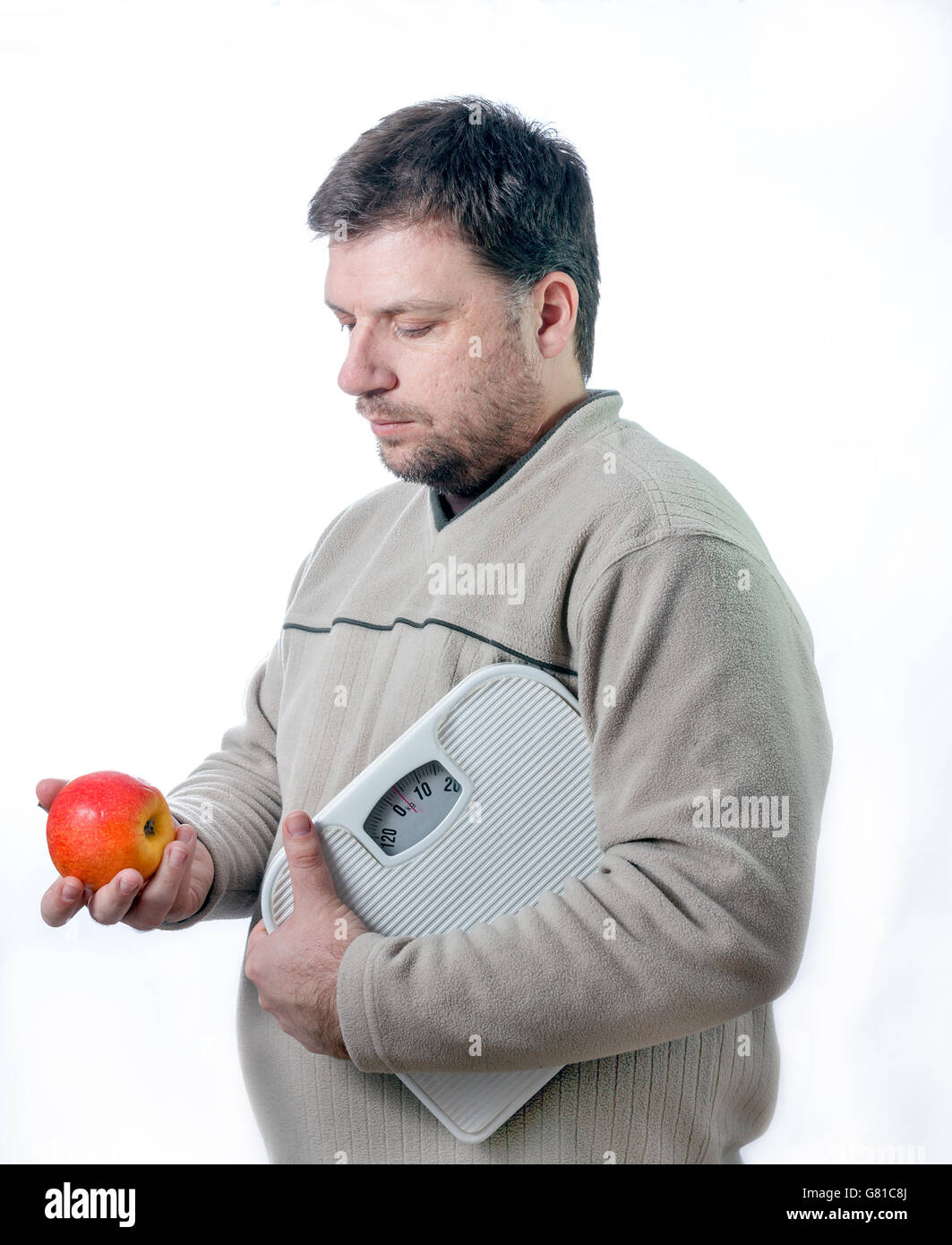 Adult men holding bathroom scale looking at a healthy apple. Staying