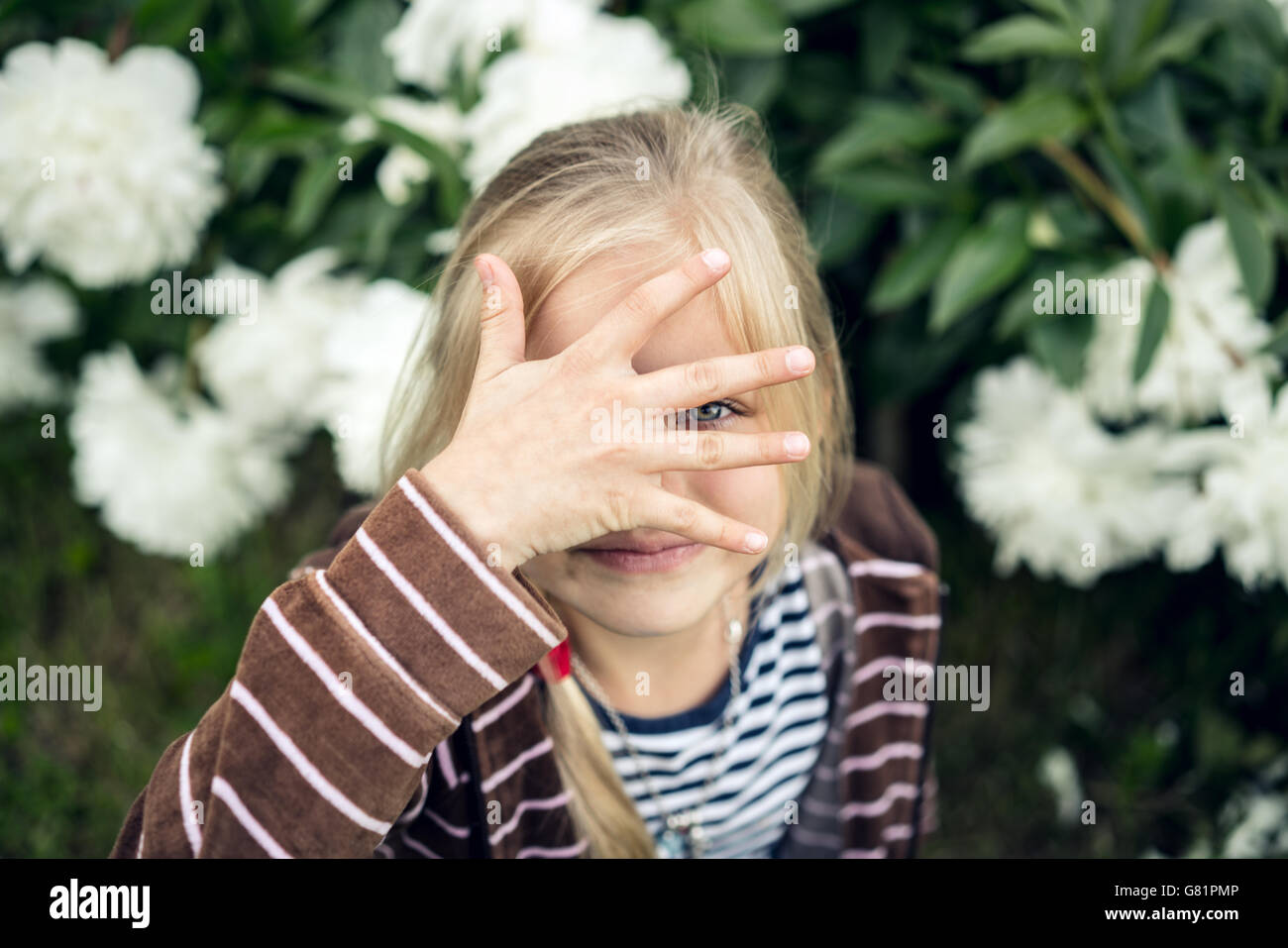 Beautiful blond girl hiding behind his hand. Stock Photo