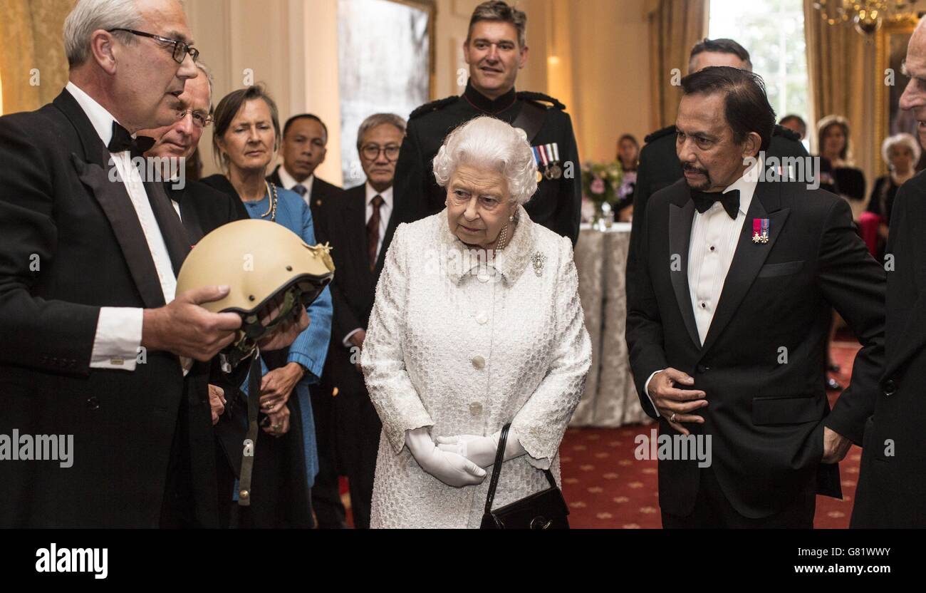 Queen Elizabeth II and the Sultan of Brunei (right) look at a helmet worn by a Gurkha soldier Corporal Tuljung Gurung in Afghanistan which was shot through by a snipers bullet during the Gurkha 200 Pageant at the Royal Hospital Chelsea, London. Stock Photo
