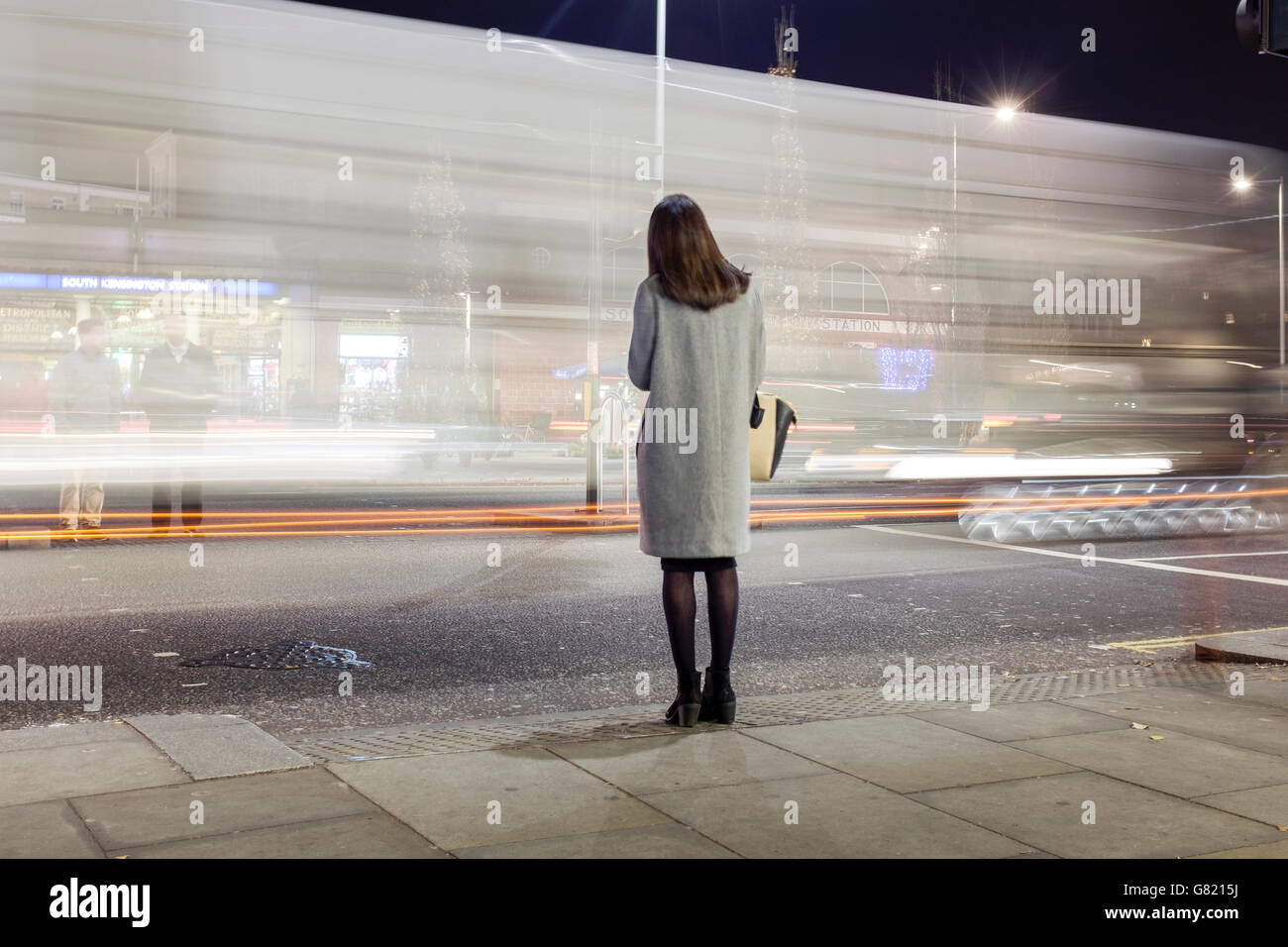 UK,London,South Kensington-Woman waiting to cross busy road at night Stock Photo