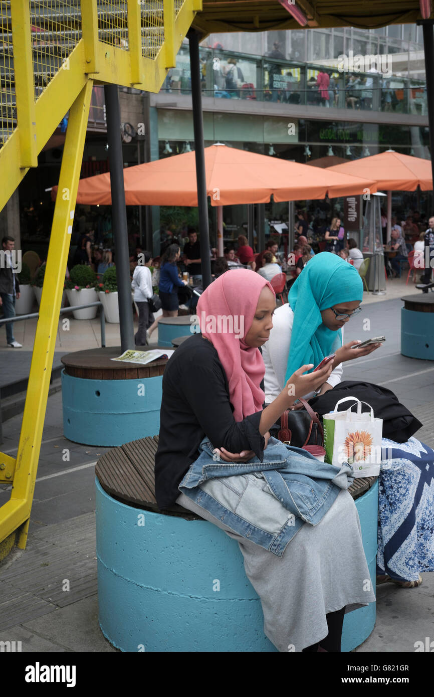 UK,London, The South Bank-young girls in colorful headscarf on their mobile phones Stock Photo