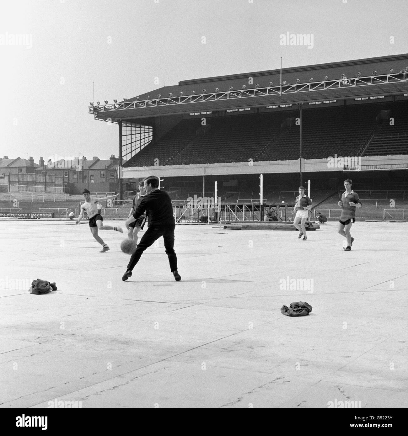 The ring for the World Heavyweight title fight is erected in the middle of the Highbury pitch while an impromptu kickabout takes place on the covered surface Stock Photo