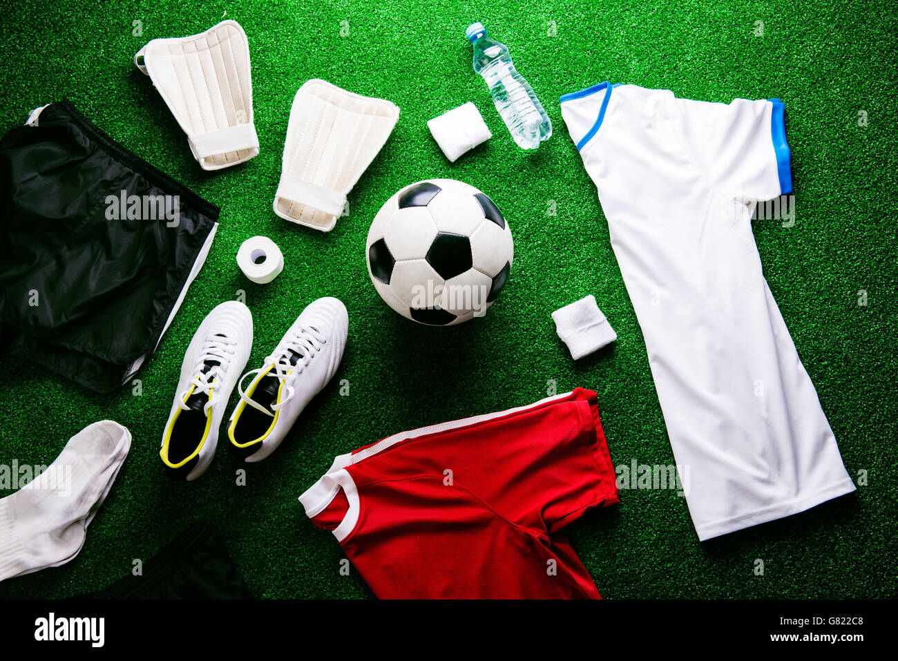 Soccer ball,cleats and various football stuff against artificial Stock Photo