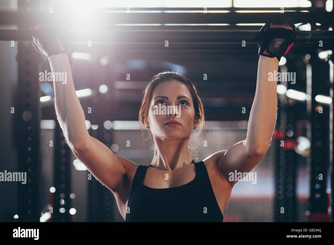 Close-up of young woman doing chin-ups at gym Stock Photo