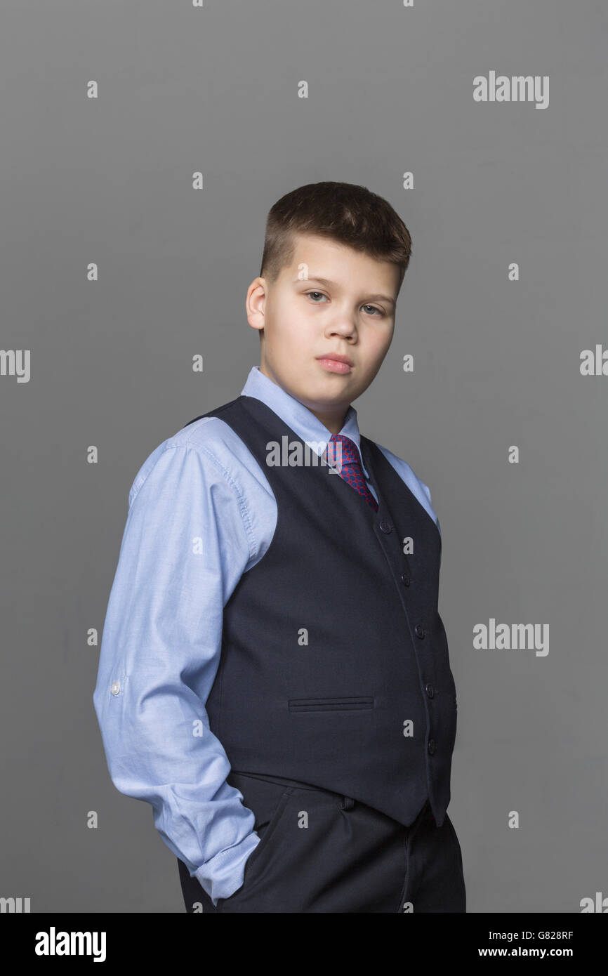 Portrait of confident boy standing against gray background Stock Photo