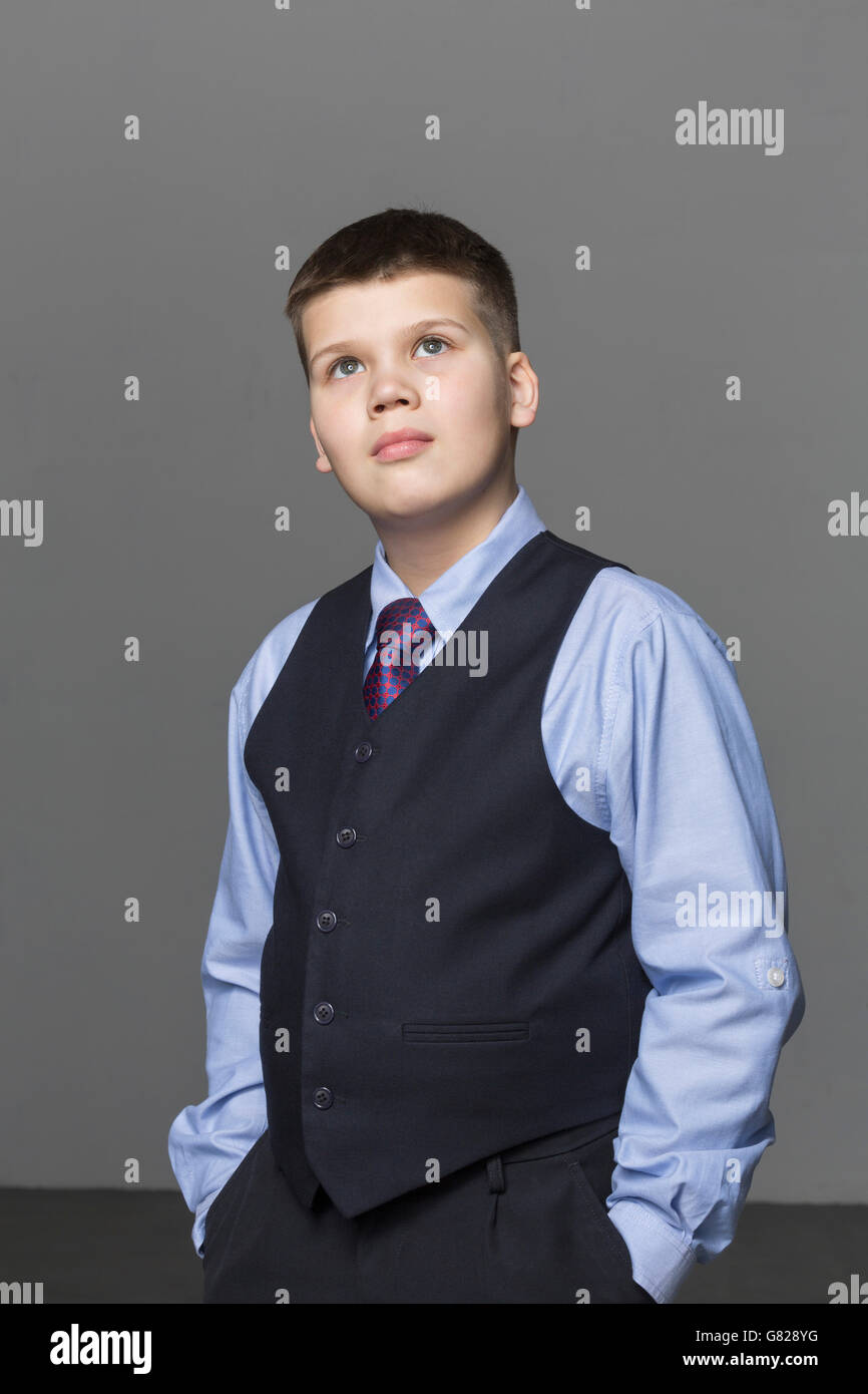Confident boy looking up while standing against gray background Stock Photo