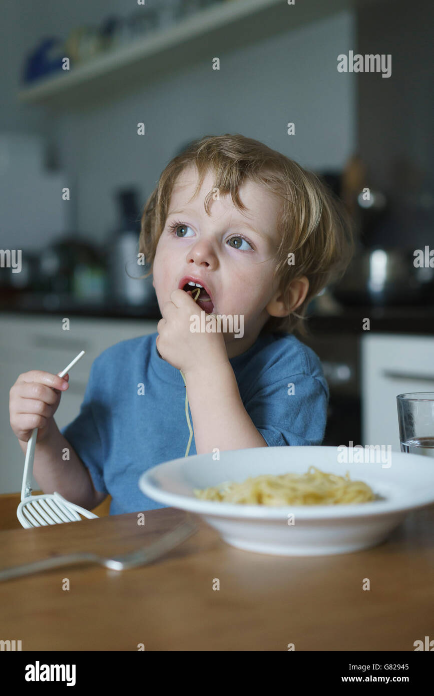 Boy eating noodles in kitchen at home Stock Photo - Alamy