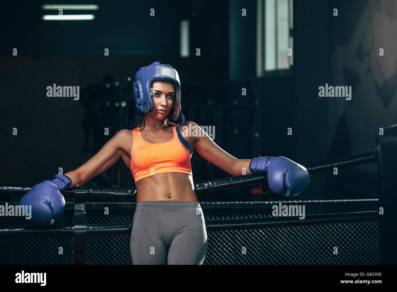 Female boxer leaning on ropes in boxing ring Stock Photo