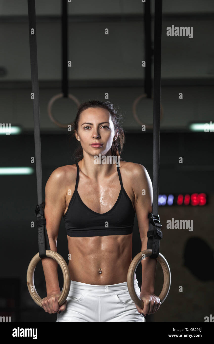 Portrait of young woman exercising on gymnastic rings at gym Stock Photo