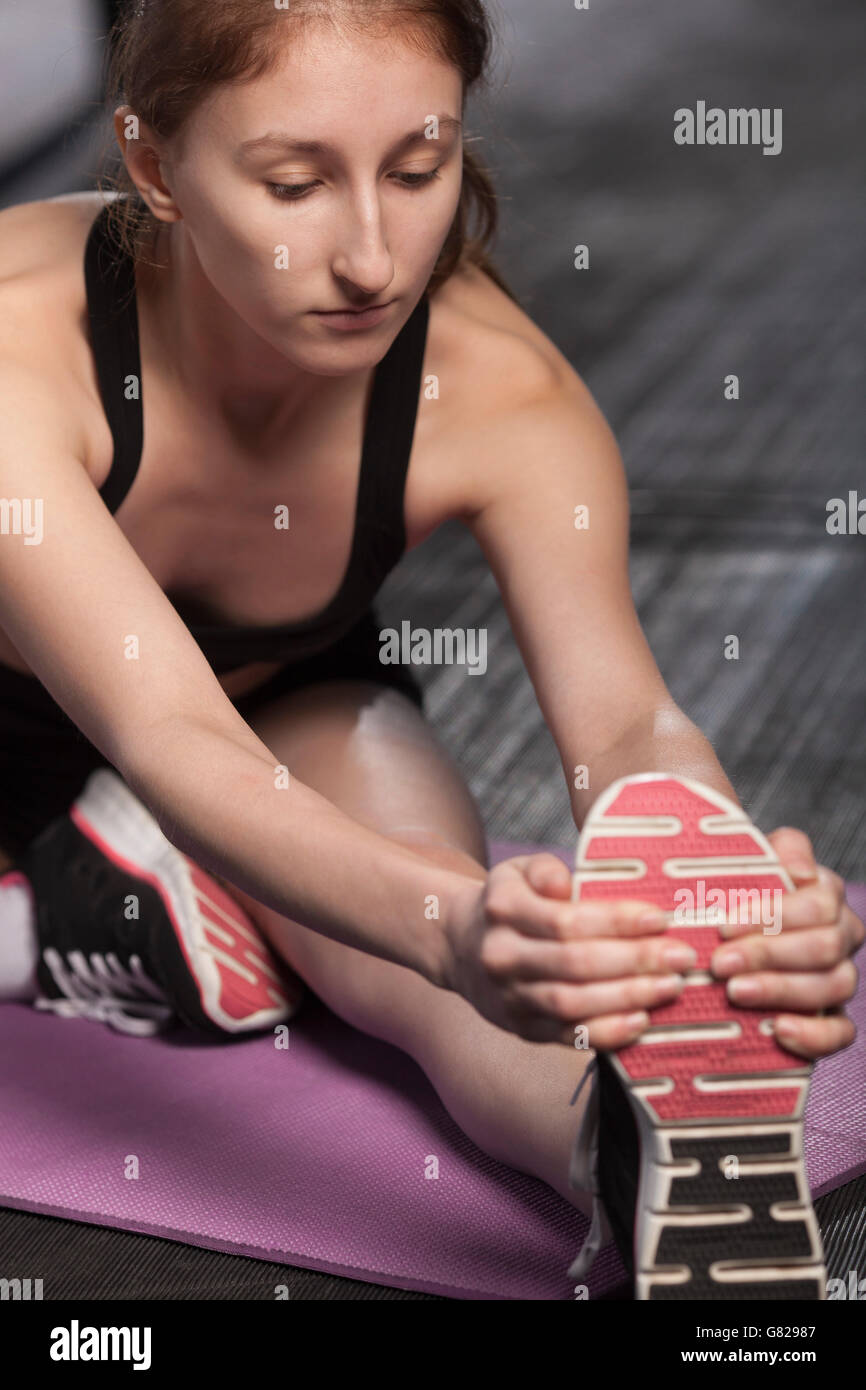Teenage girl stretching in gym Stock Photo