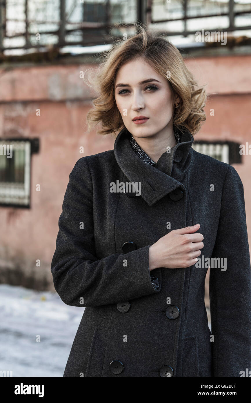 Portrait of confident young woman wearing long coat outdoors Stock Photo