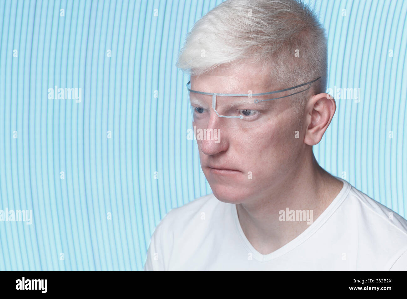 Close-up of albino man wearing protective eyewear against blue background Stock Photo