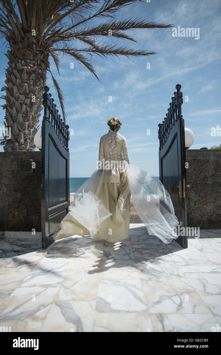 Rear view of bride walking towards beach Stock Photo