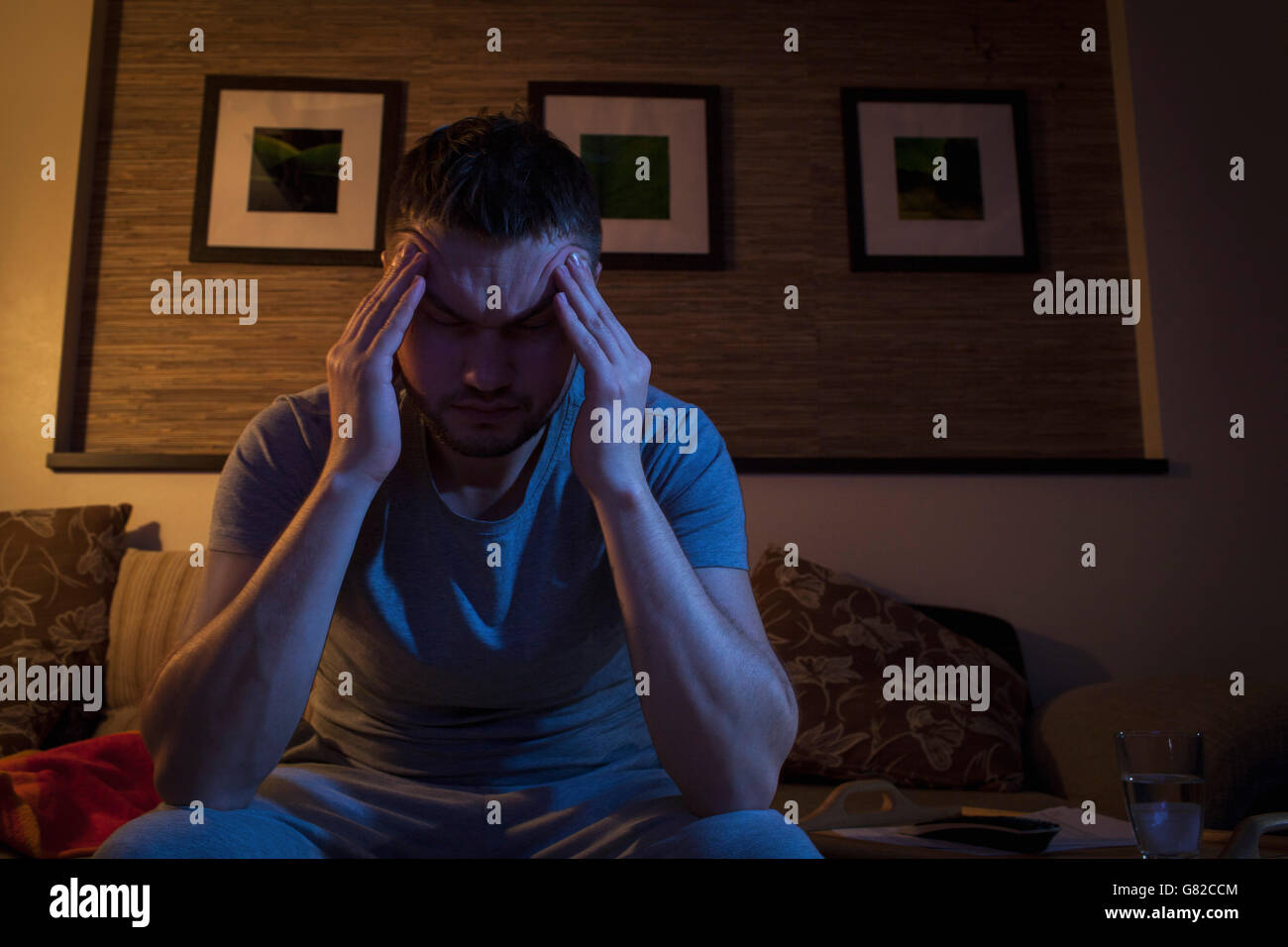 Man suffering from headache while sitting on sofa at home Stock Photo