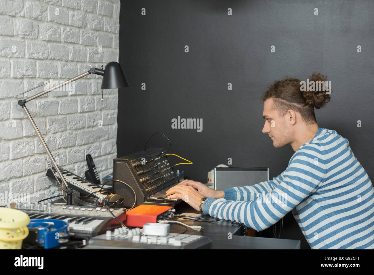 Side view of young man playing synthesizer while sitting at table Stock Photo
