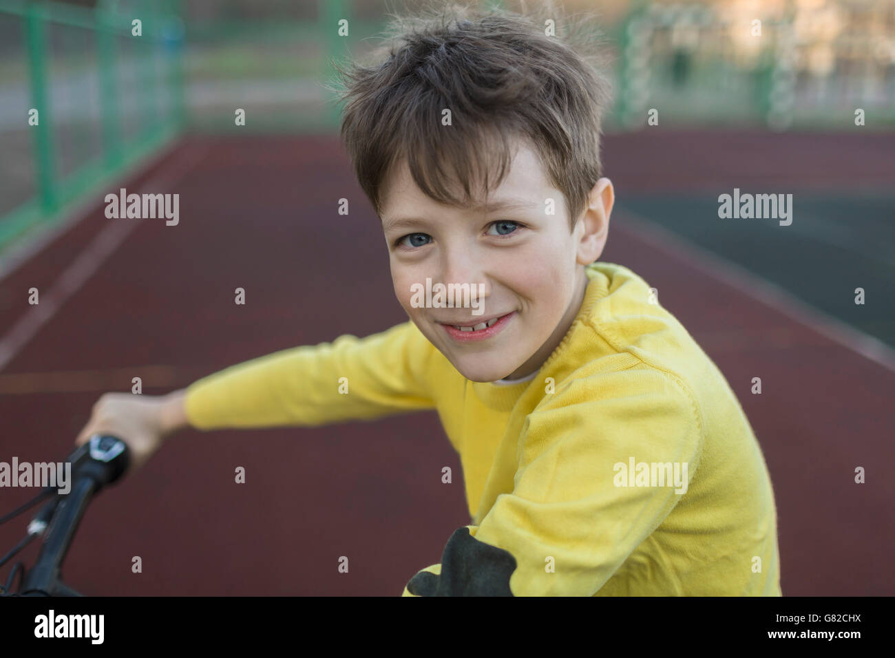 Portrait of smiling boy cycling in court Stock Photo