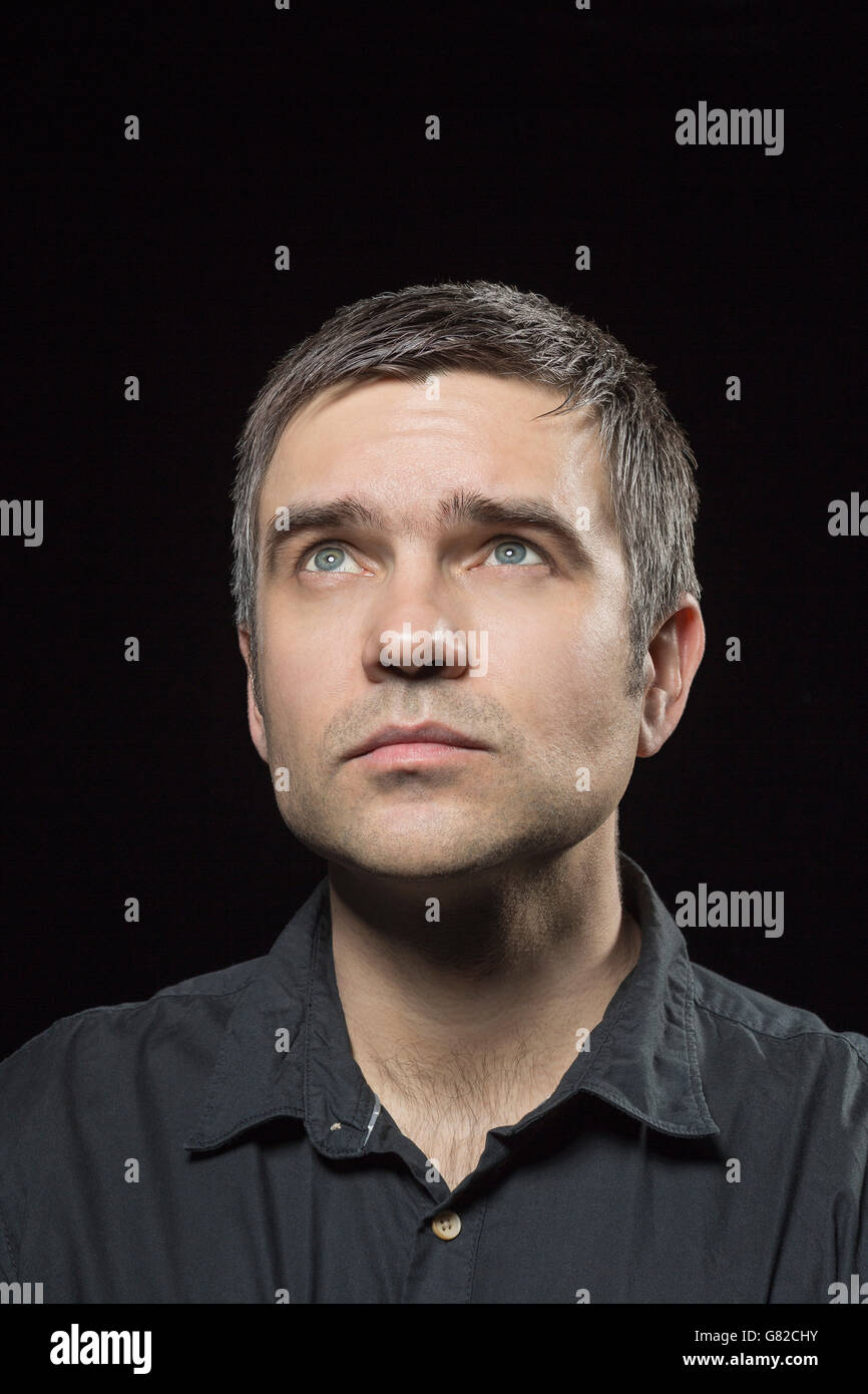 Close-up of man looking up against black background Stock Photo