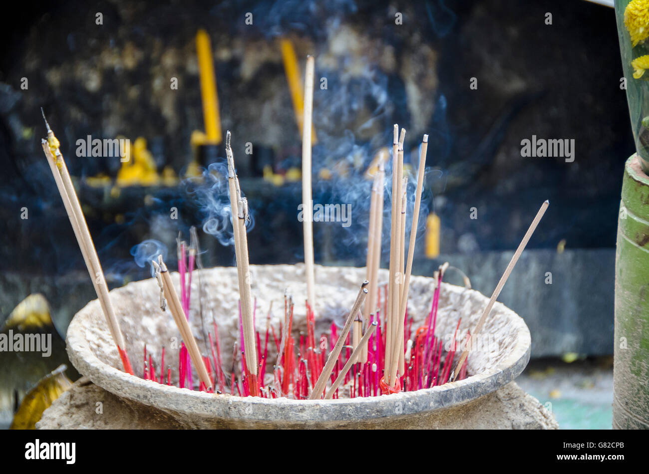 Smoke emitting from incense sticks in container at temple Stock Photo