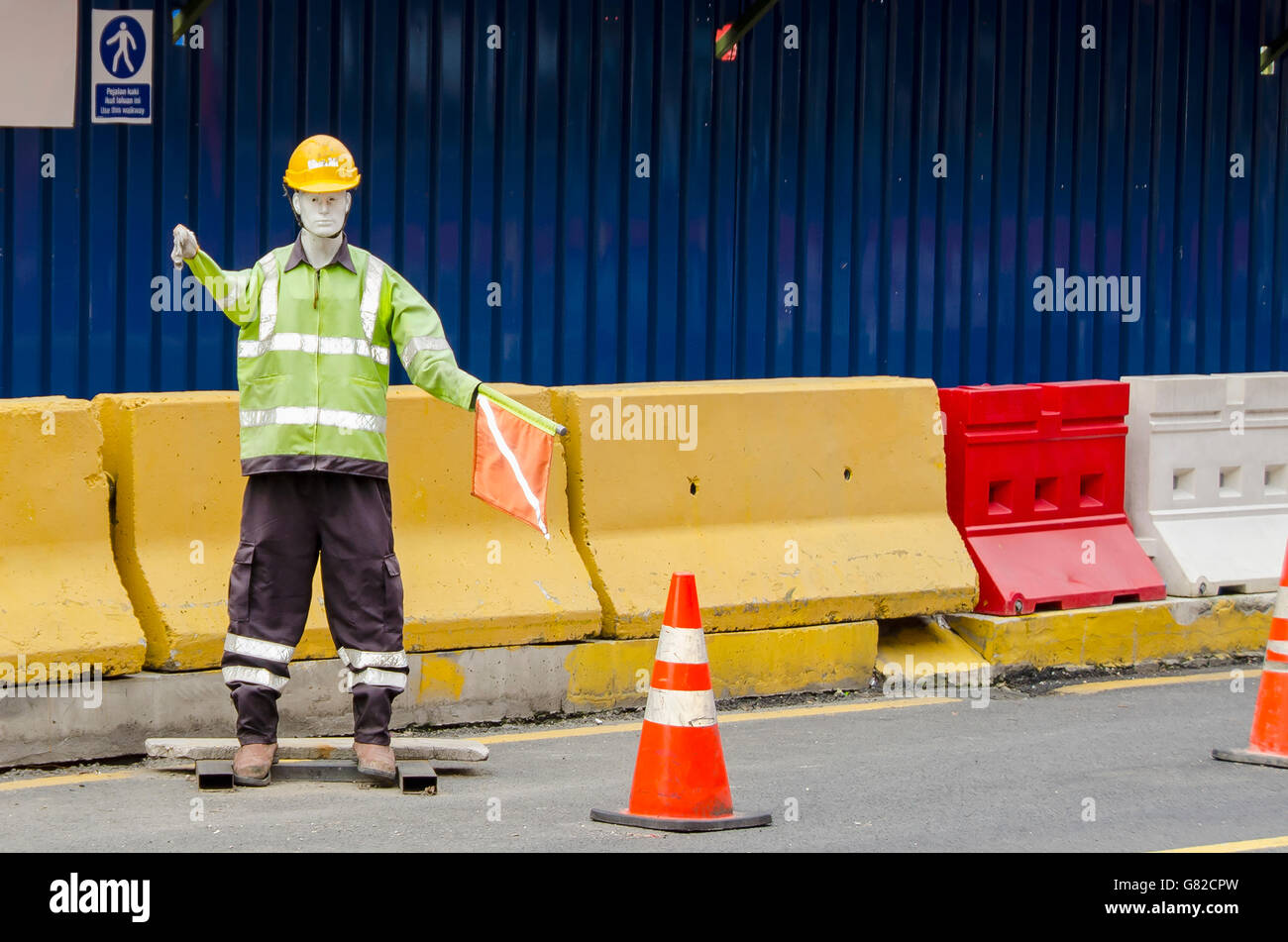 Mannequin in reflective clothing against barricades on road Stock Photo
