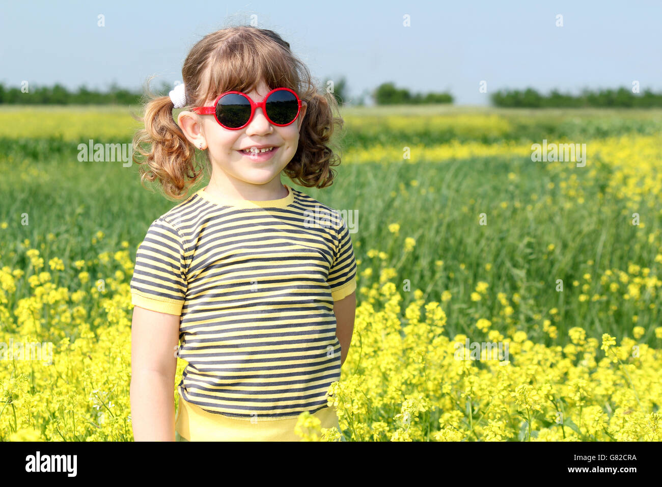 little girl posing in yellow flowers field Stock Photo - Alamy