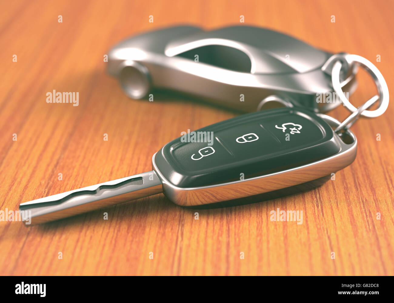 Car key with a car shaped keychain, on a wooden table. Stock Photo