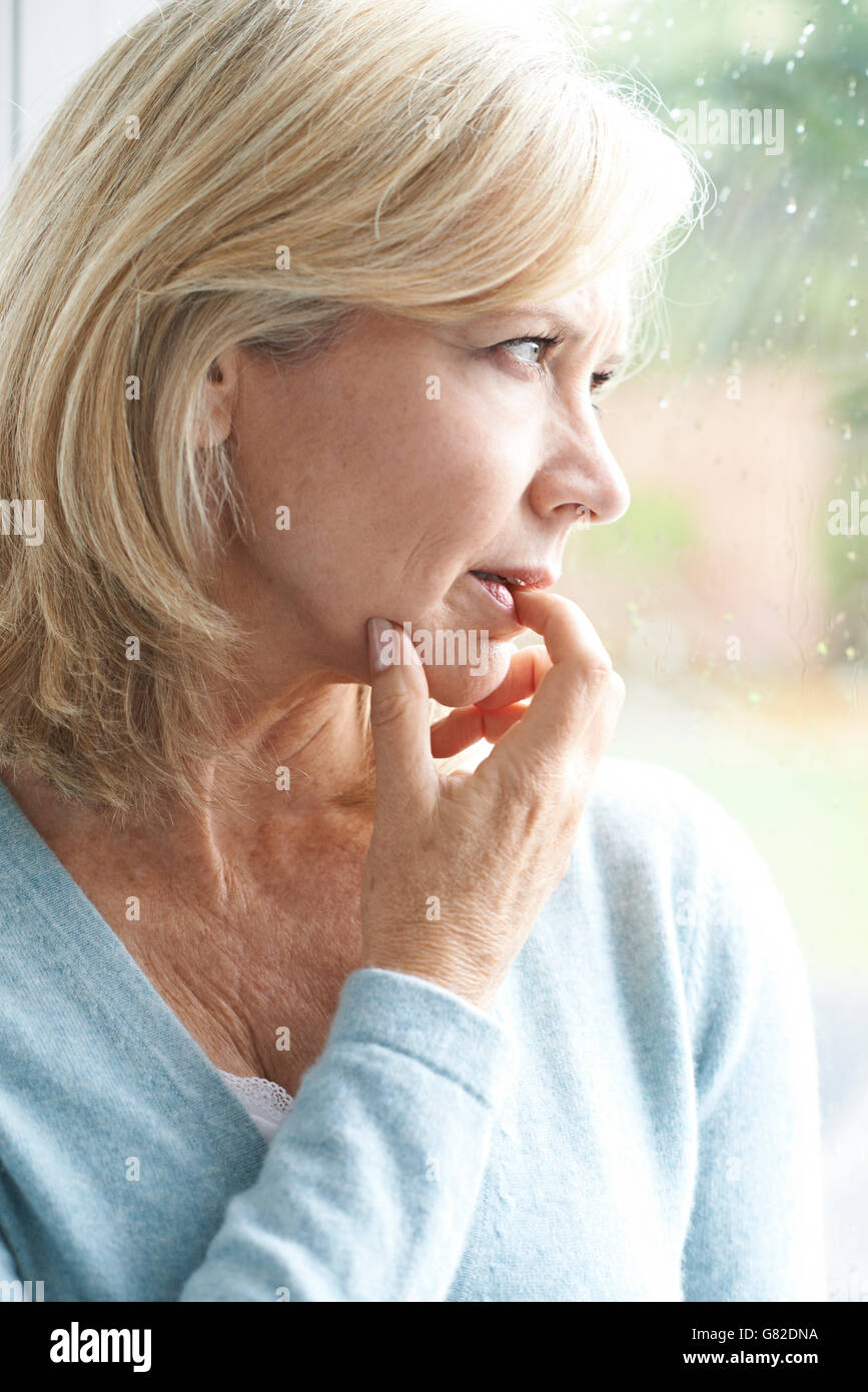 Sad Mature Woman Suffering From Agoraphobia Looking Out Of Window Stock Photo