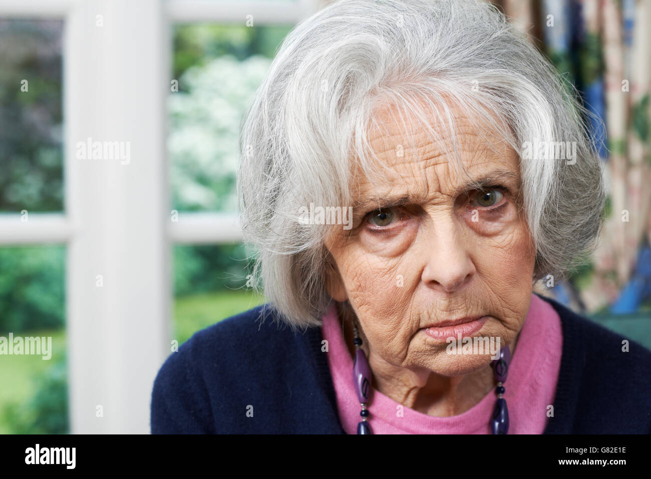 Head And Shoulders Portrait Of Angry Senior Woman At Home Stock Photo