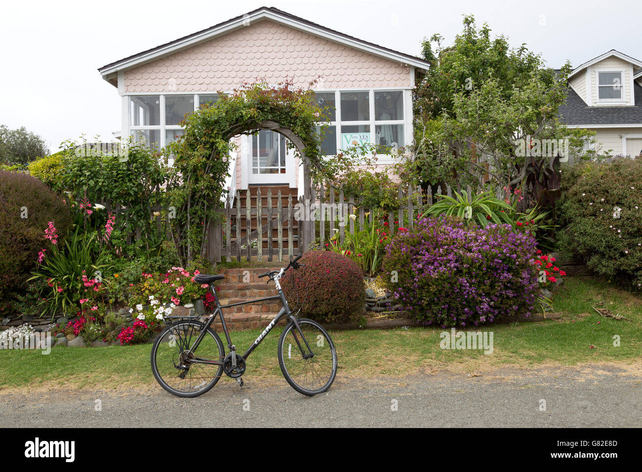 gardens, flowers, picket fence and bike in front of small house in Mendocino, California. Stock Photo